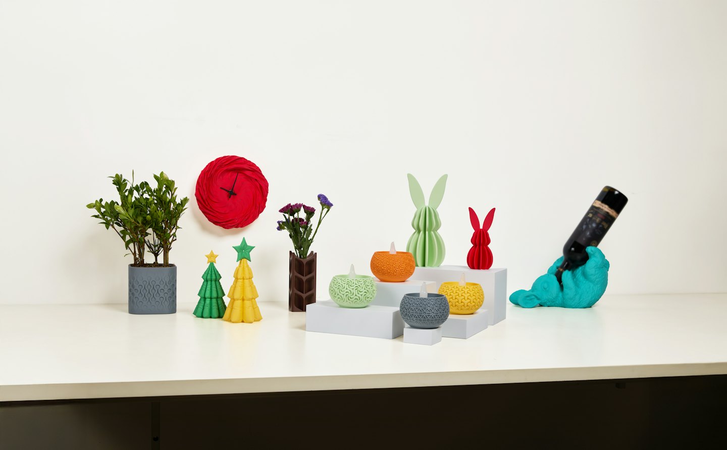 Bunte 3D-gedruckte Objekte und Pflanzen auf einem weißen Tisch.