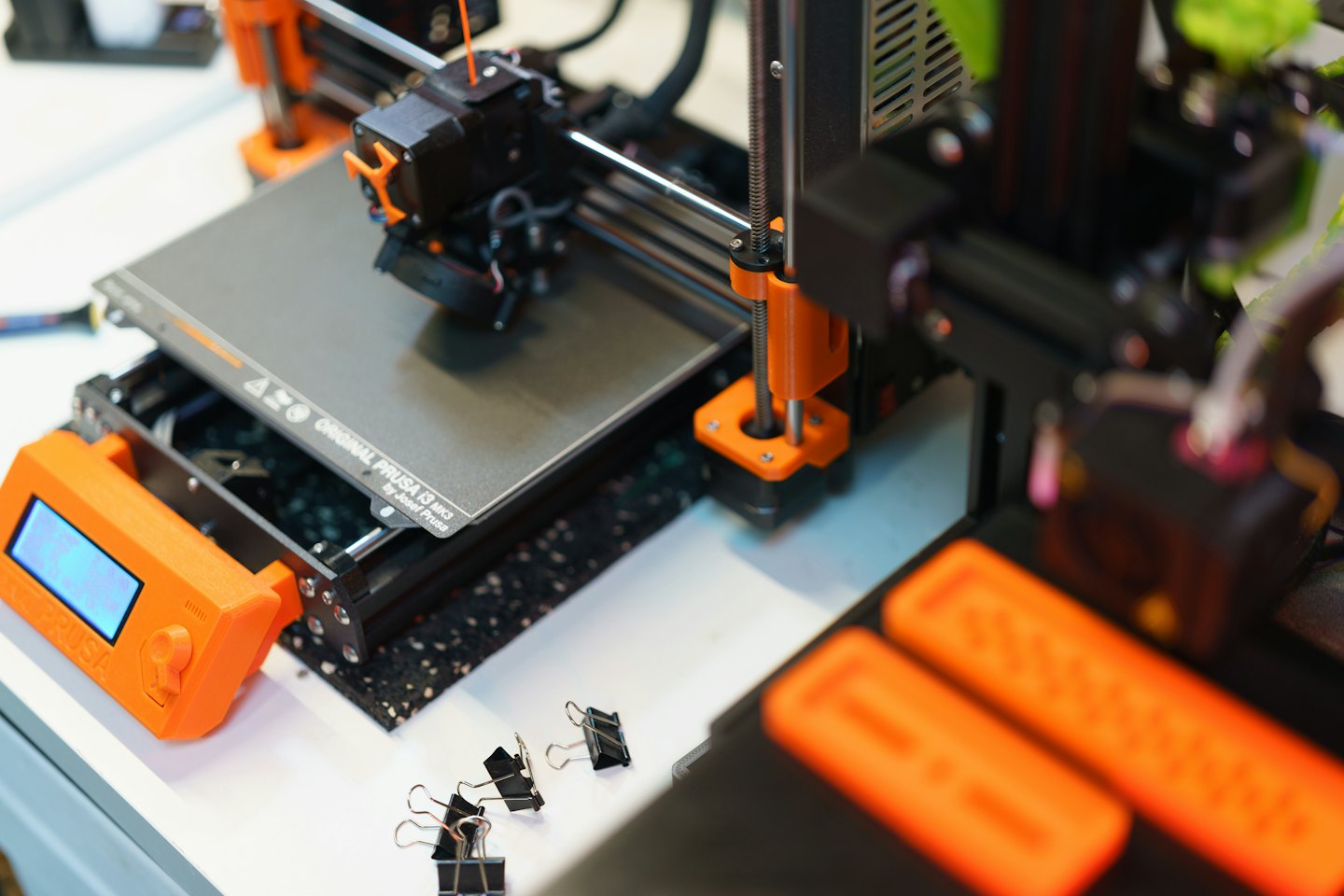 3D-Drucker mit orangen Komponenten in einer Werkstatt.