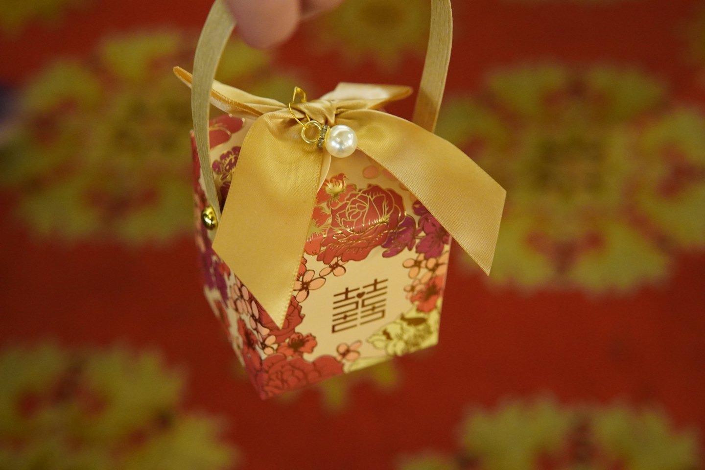 Hand hält dekorative Geschenkbox mit doppeltem Glückssymbol.